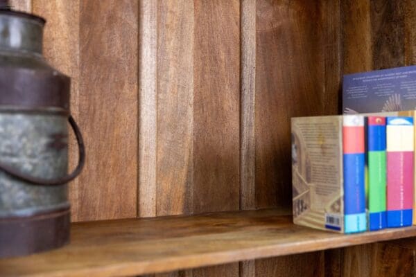 A wooden shelf with some books and a bottle of wine