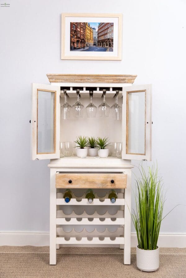 A white cabinet with wine glasses and plants on top of it.