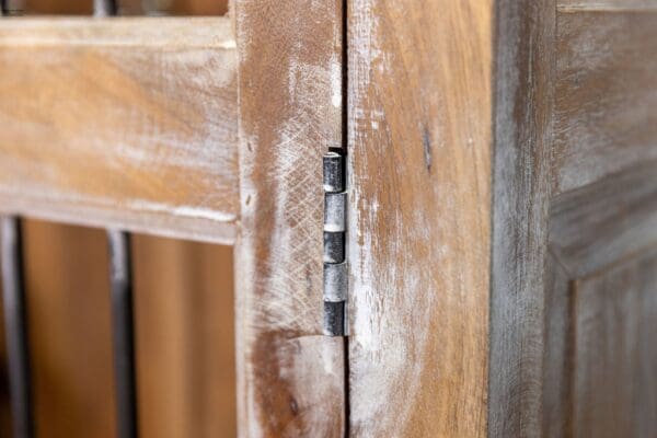 A close up of the hinge on an old wooden door.