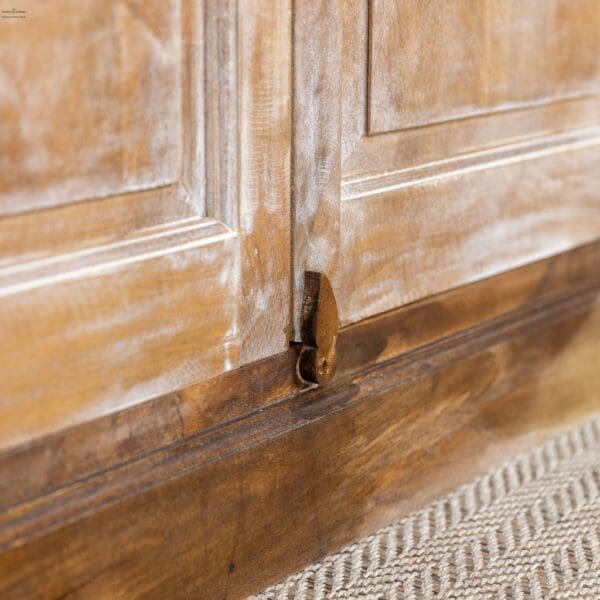 A close up of the door handle on a wooden cabinet.