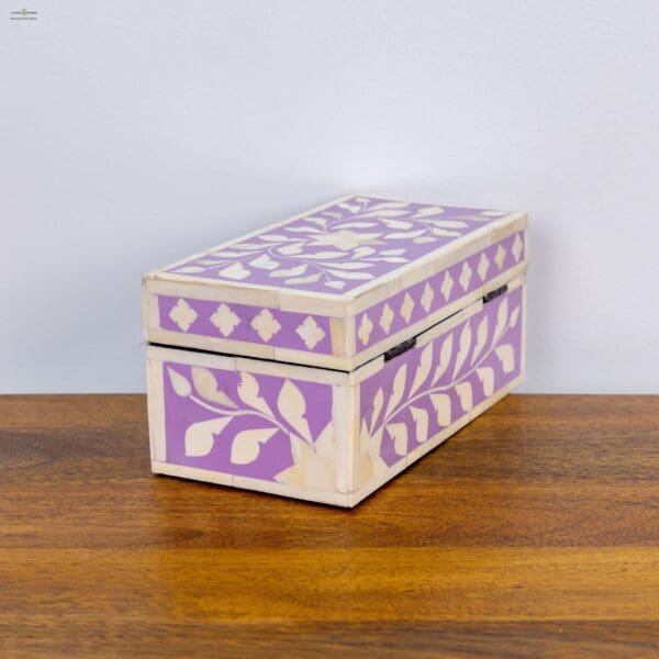 A wooden box with purple and white design on top of a table.