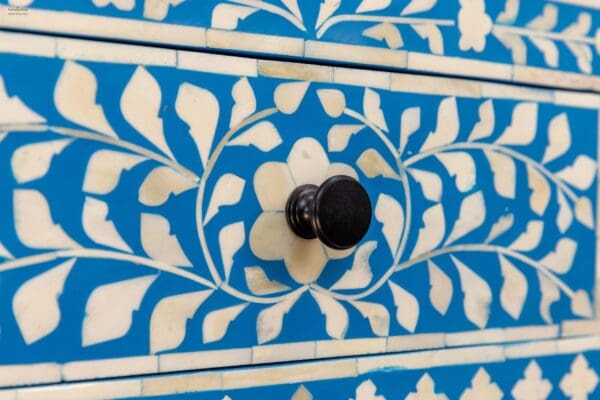 A close up of the knob on a blue and white cabinet.