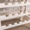 A white rack with many bottles of wine on it.