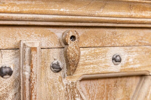 A close up of the handle on an old wooden cabinet.