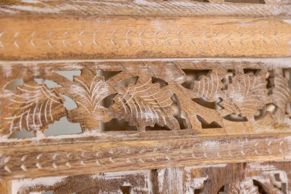 A close up of the carved wood frame on an antique chair.