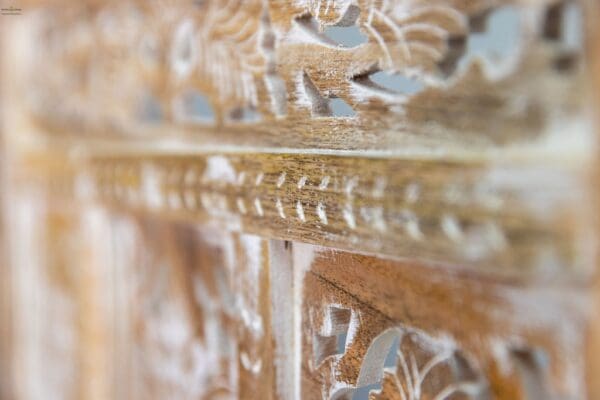 A close up of the wood carving on a wooden table.