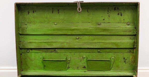 A green wooden box with two drawers and a metal handle.