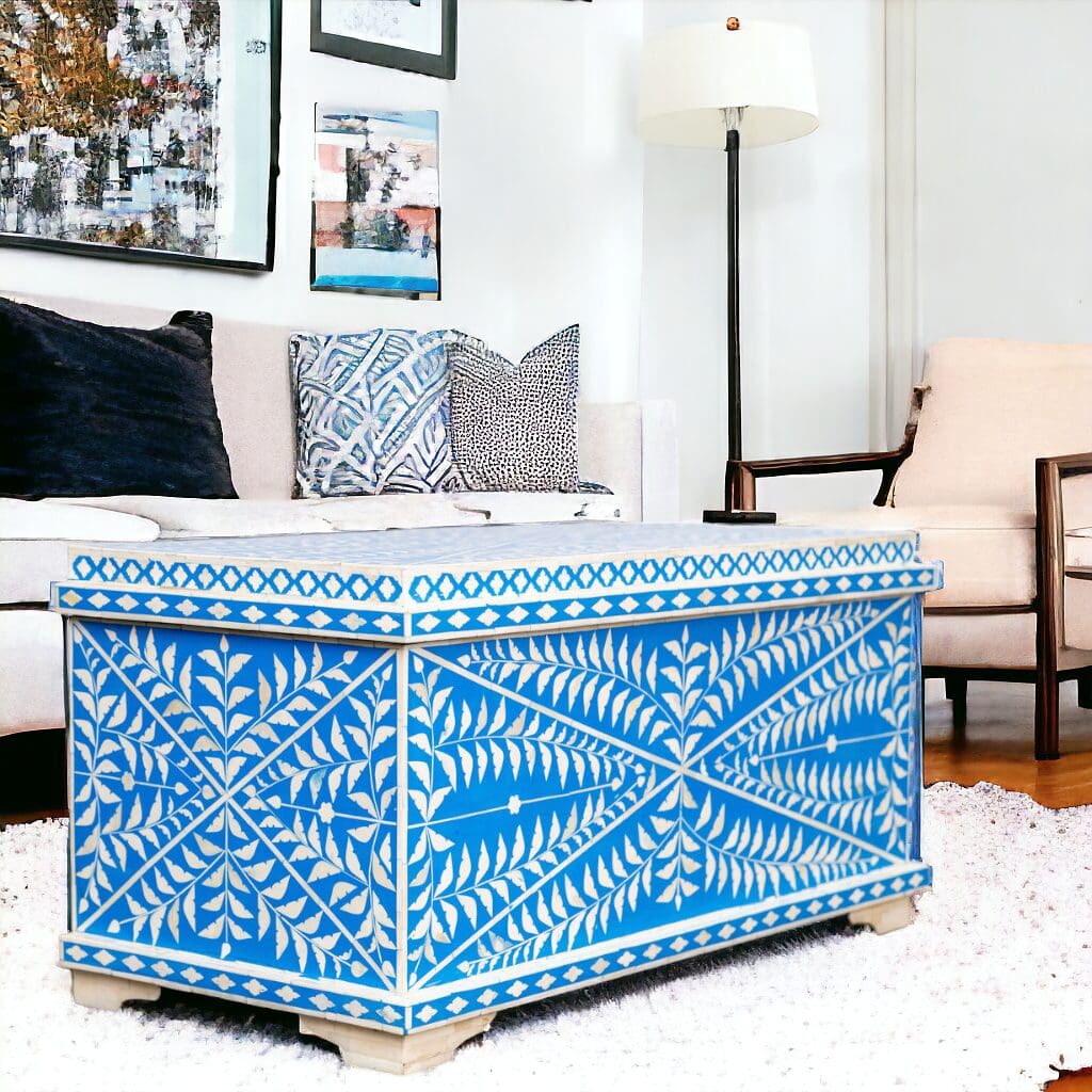 A blue and white trunk sitting in front of a couch.