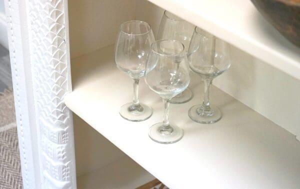 A shelf with four wine glasses on it.