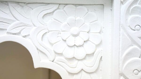 A white flower is carved into the corner of a table.