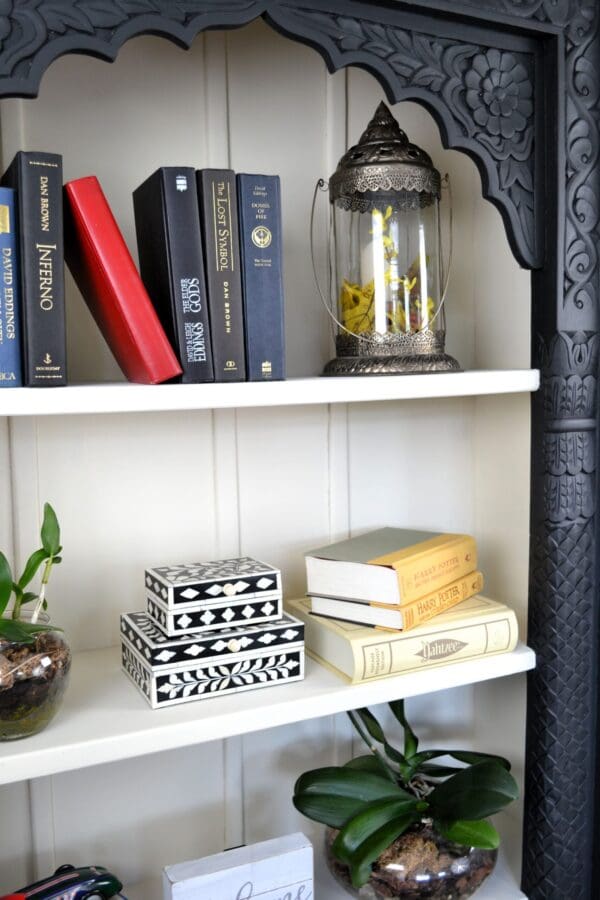 A bookshelf with books and a lantern on it.