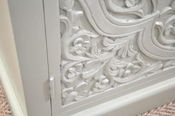 A close up of the door and frame of an ornate cabinet.