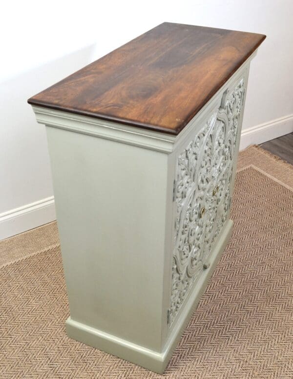 A white cabinet with wood top and floral design.