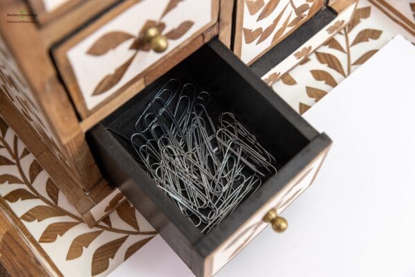 A drawer with many paper clips in it