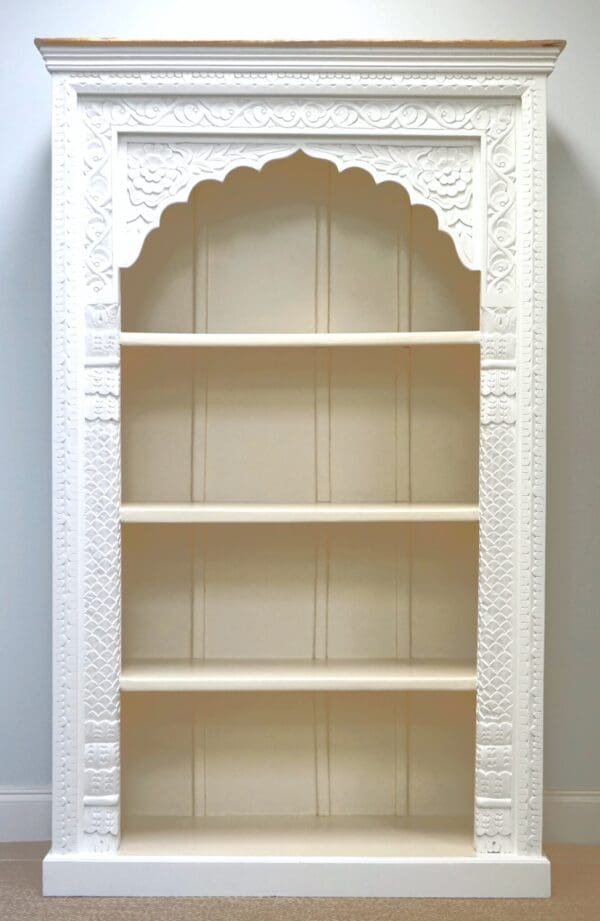 A white bookcase with carved details and arched top.