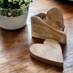 A set of four heart shaped coasters with a holder staged on a countertop. Coaster Set