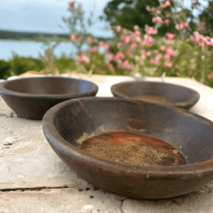 Vintage wooden bowl. Three bowls sitting on a table outside near water.