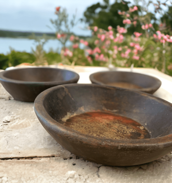 Vintage wooden bowl. Three bowls sitting on a table outside near water.