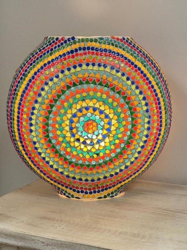 A colorful vase sitting on top of a wooden table.