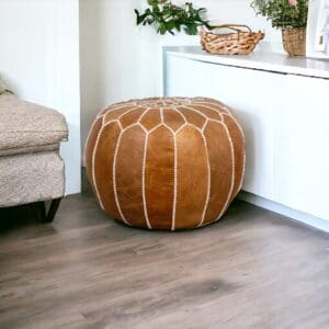 A brown ottoman sitting in front of a wall.