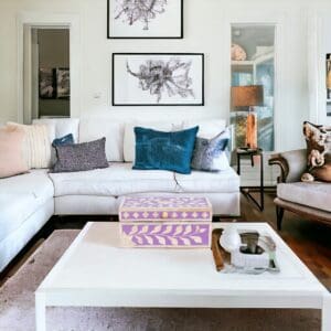 A living room with white furniture and a coffee table.