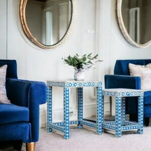 A living room with blue chairs and two tables