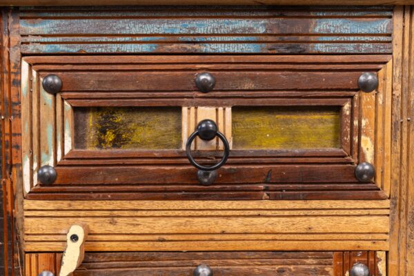 A close up of the door handle on an old wooden cabinet.