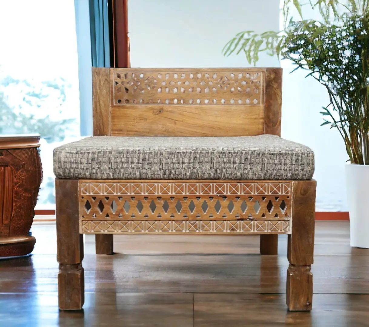 Oversized square chair, hand-crafted solid mango wood with cut out details. Staged in a living room.