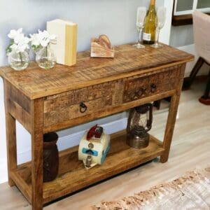 Natural wood console table with 2 drawers and lower shelf, hand-crafted staged in a home with decorative accents.