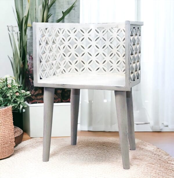 hand-crafted solid mango wood chair in a white finish, curved back with a lattice cut out, staged in a sunny room.