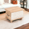 Small artisanal solid wood trunk with hand-carved front panel staged in a living room