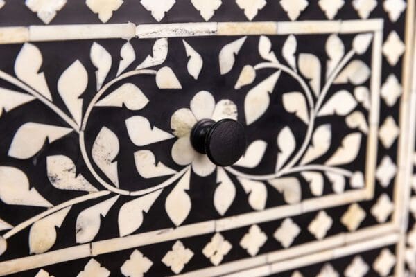 A close up of the knob on a black and white dresser