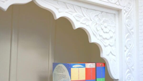 A white wall with a decorative arch and a colorful book.