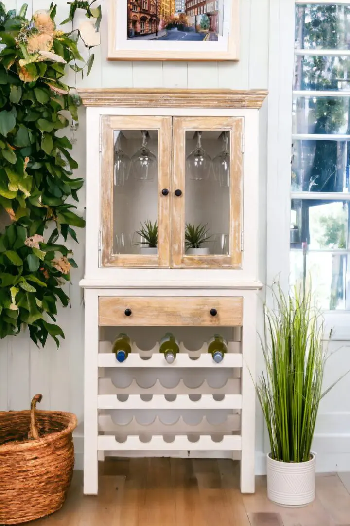 A white and wood cabinet with wine bottles on top of it.
