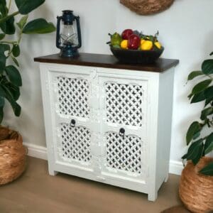 white carved cut-out buffet cabinet staged in a home with plants