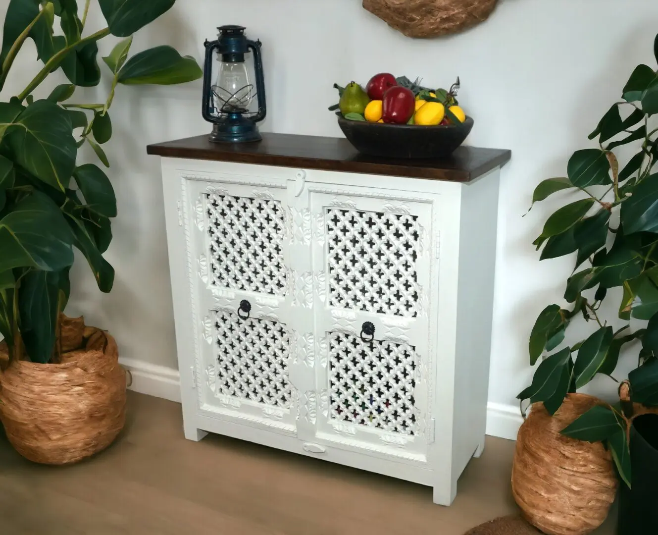 white carved cut-out buffet cabinet staged in a home with plants