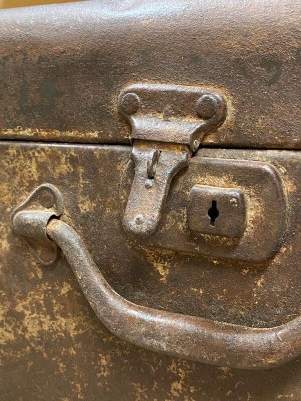 A close up of the handle and lock on an old metal box.