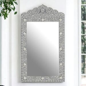 A gray and white decorative accent mirror with a decorative frame on the wall.