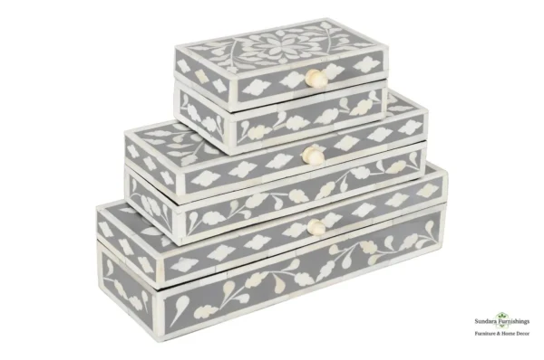 A set of four grey boxes with white floral designs.