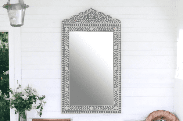 A mirror with a decorative frame on the wall.