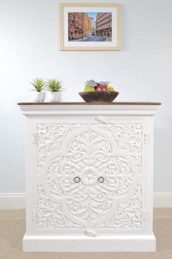 A white cabinet with carved details and a wooden top.