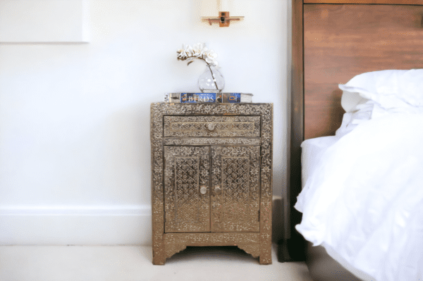 Stunning white metal side table, hand embossed with 1 drawer and 2 doors. Staged in a bedroom as a nightstand