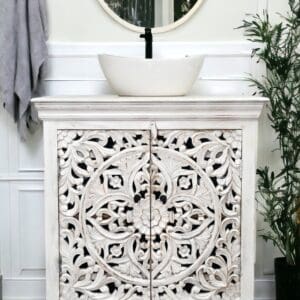 White carved cabinet with sink above.