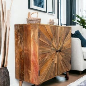 A solid wood cabinet with a sunburst design sitting in the middle of a living room.