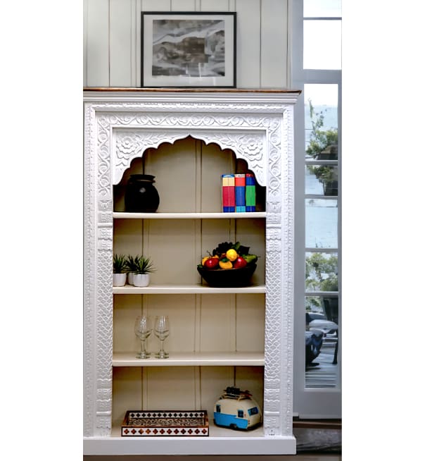 A white bookcase with a carved arch on the top.