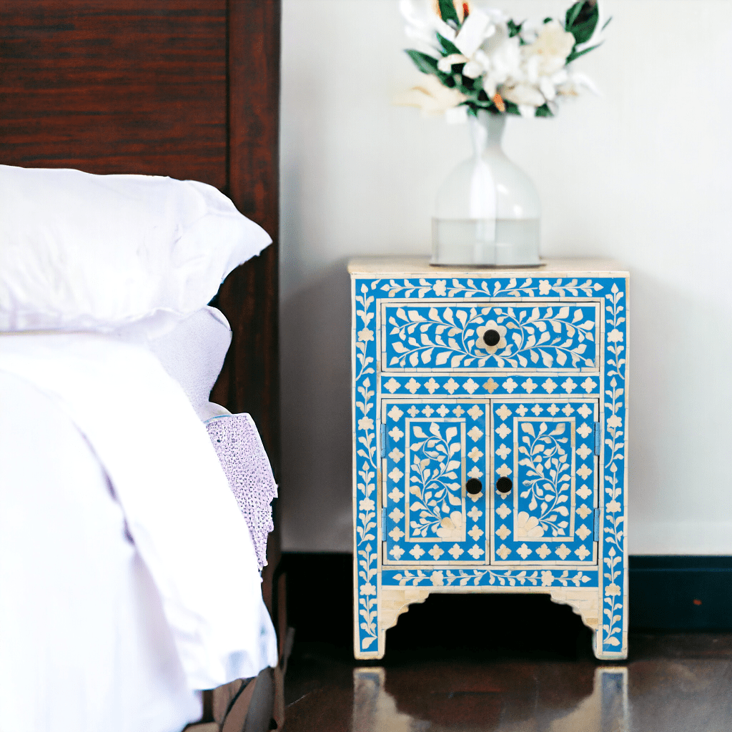 A blue and white nightstand in front of a bed.