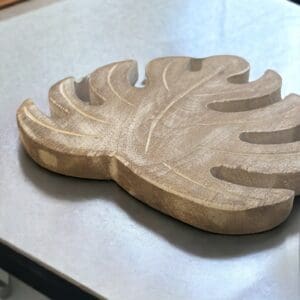 hand crafted set of four wooden leaf trivets. Close up picture of one on a kitchen countertop