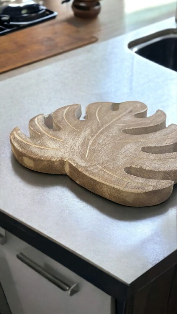 hand crafted set of four wooden leaf trivets. Close up picture of one on a kitchen countertop