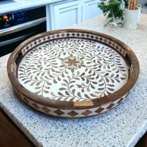 Large round teak inlay tray staged on a kitchen counter