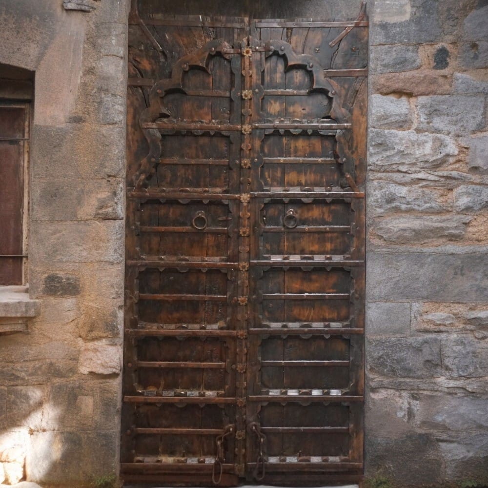 A pair of vintage ornate doors, set in a stone wall.